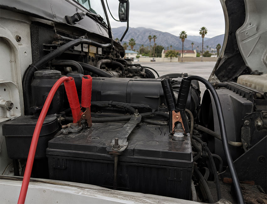 Jumper cables connected to a commercial box truck battery for roadside assistance in Glendale, California